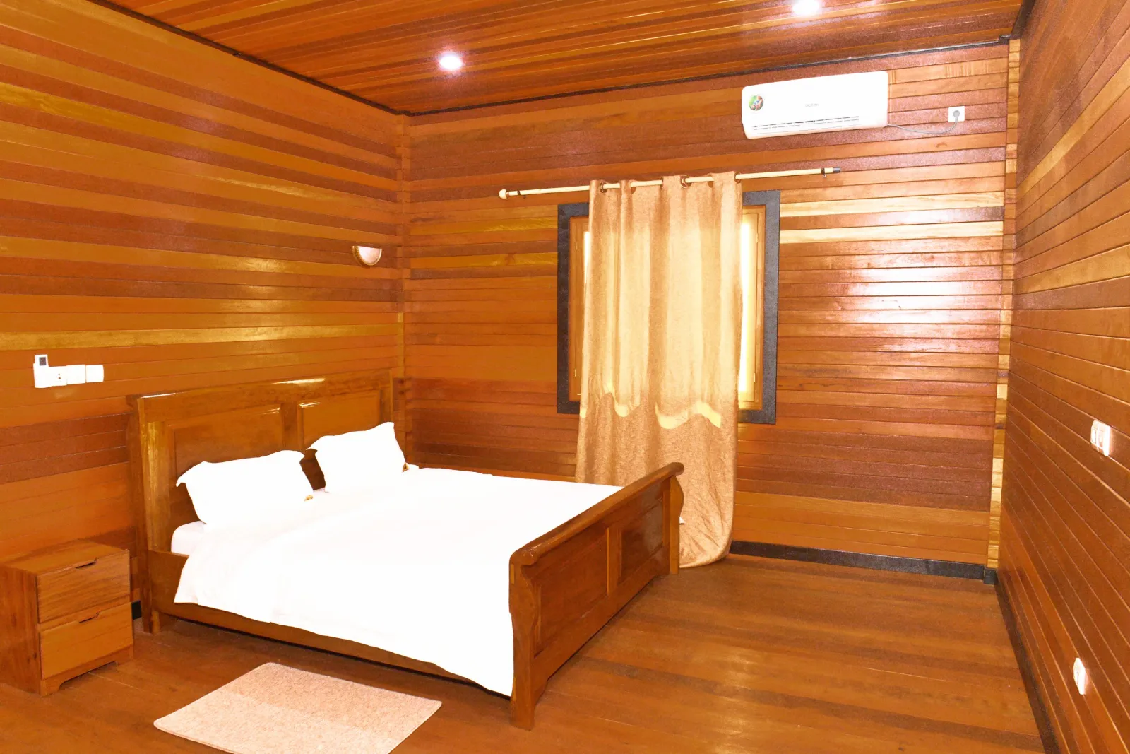 Une chambre habillée de bois, avec un grand lit, à La Cité des Grands Lacs.