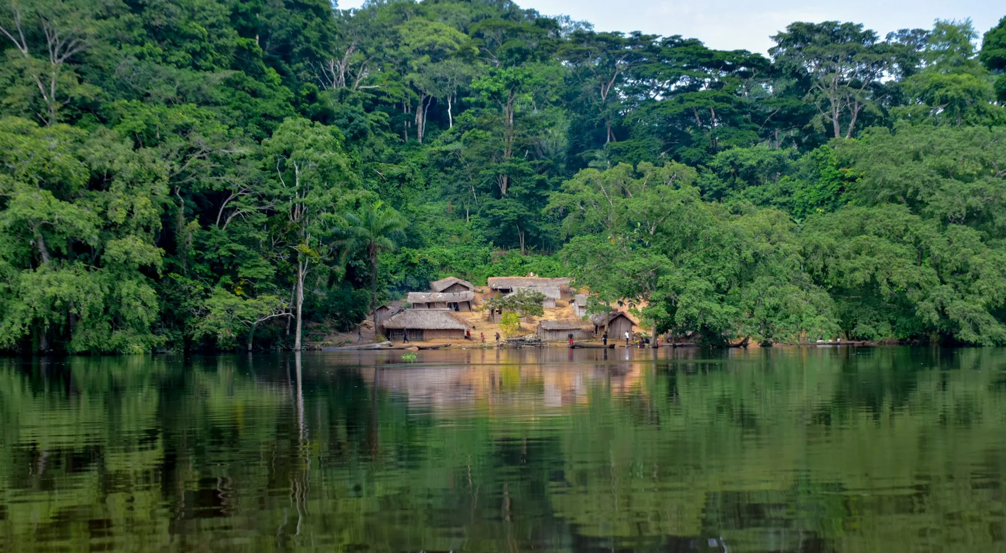 Le village niché dans la forêt, au bord de l’eau calme.